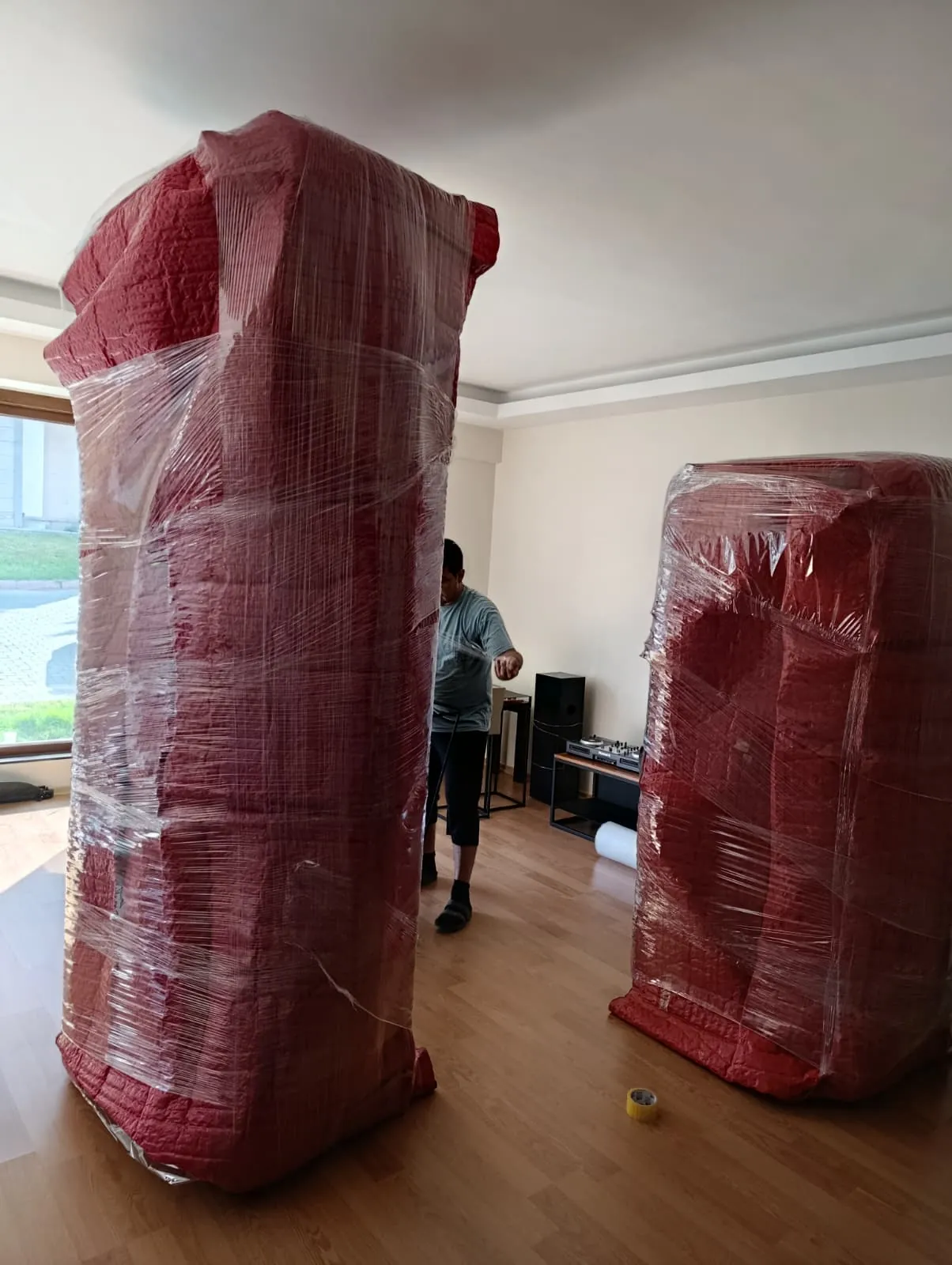 Pencere ışığında streç filmli iki kırmızı örtülü gardırop.