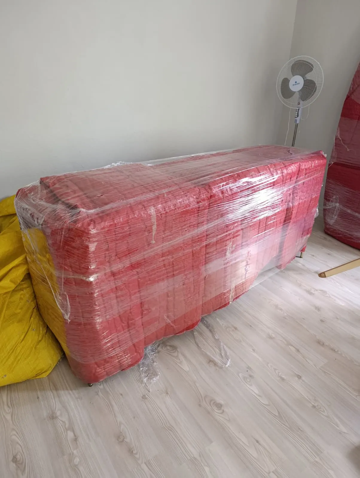 Kırmızı örtü ve streç filmle paketlenmiş uzun mobilya.