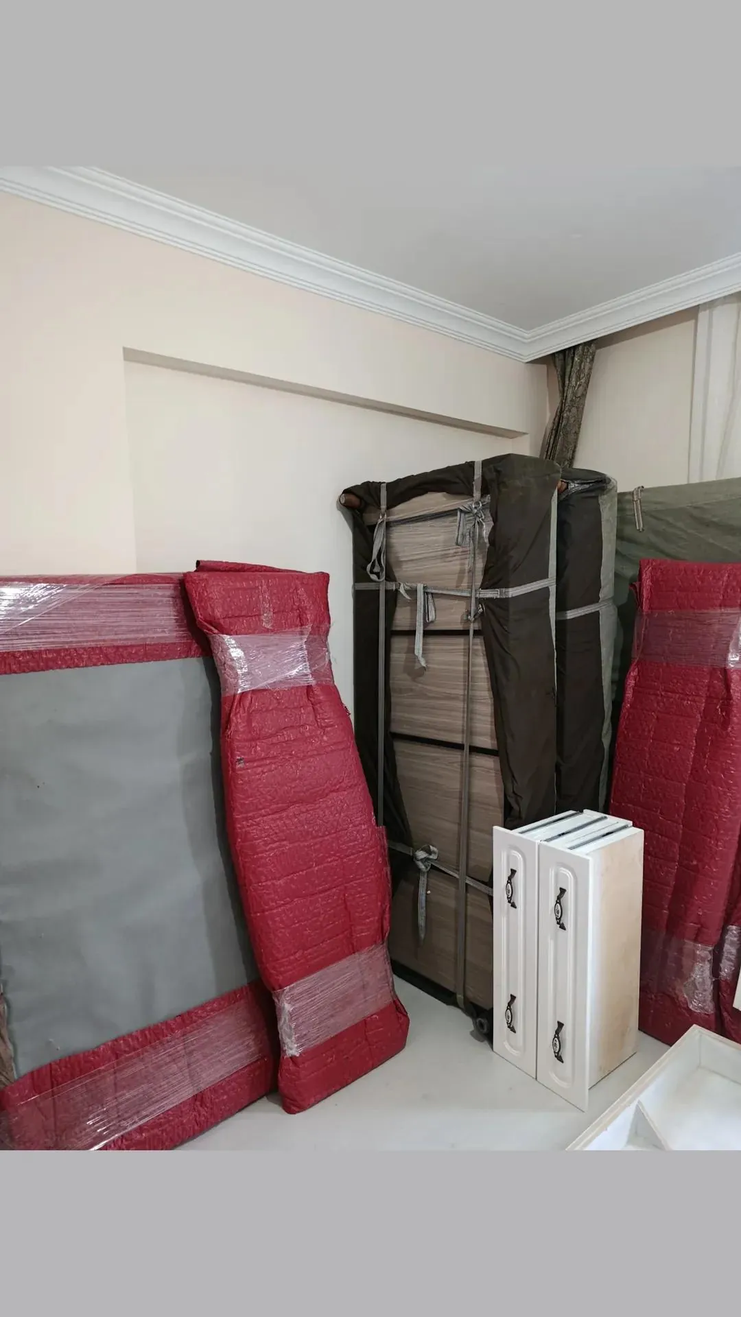 Kırmızı koruyucu örtülü yatak parçaları ve bağlanmış dolap.