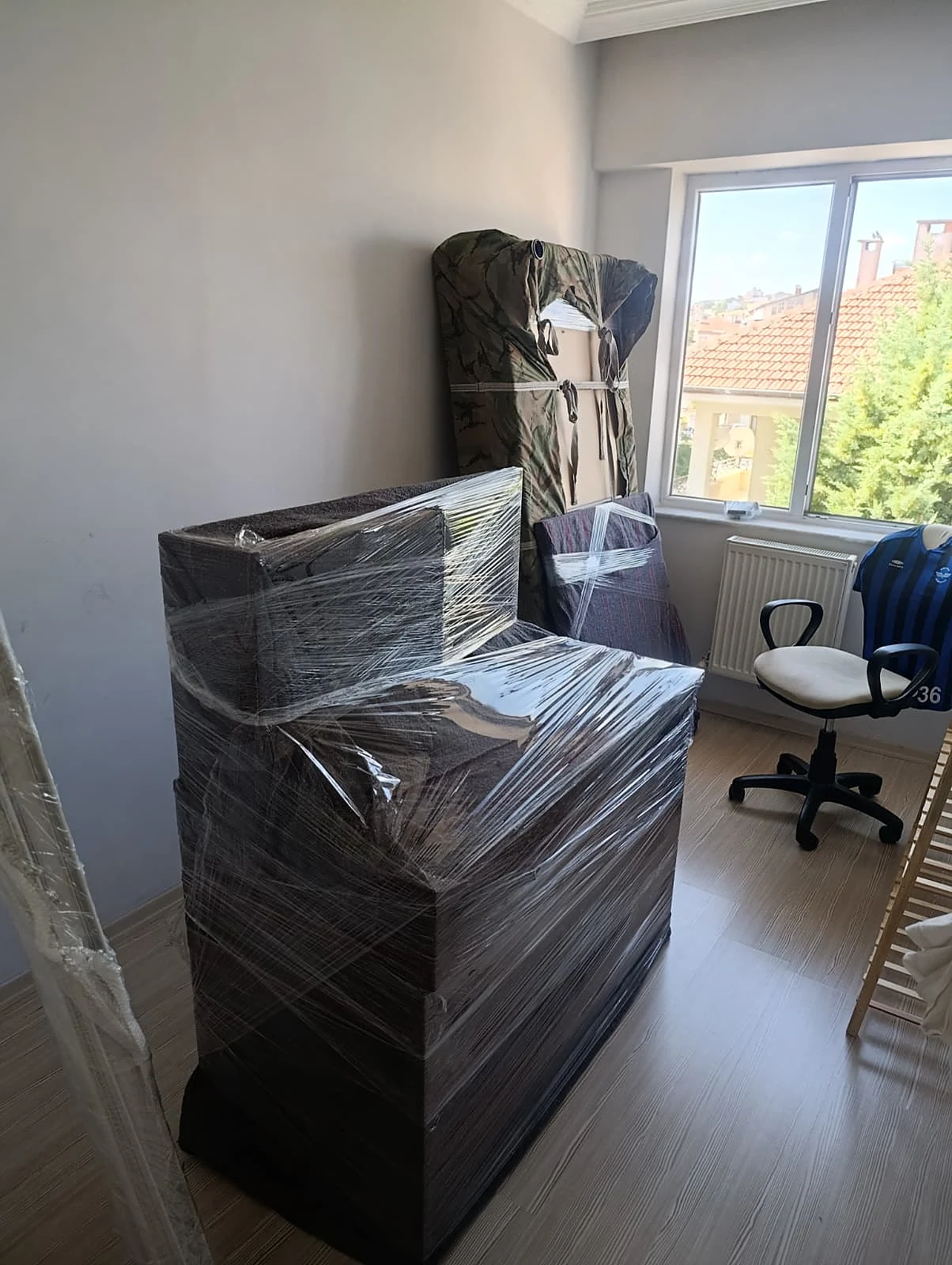 Streç filmli mobilya, kamuflaj örtülü dolap ve ofis koltuğu.