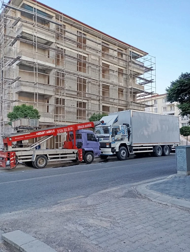 Hasan Yavuz kiralık asansör aracı ve Yavuzlar kapalı kasa kamyonu, bina önünde.
